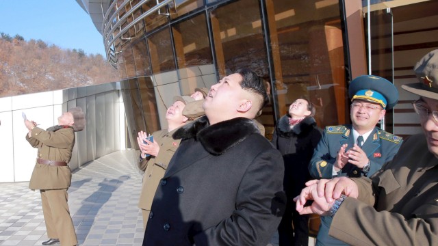North Korean leader Kim Jong Un (C) watches a long range rocket launch into the air in North Korea