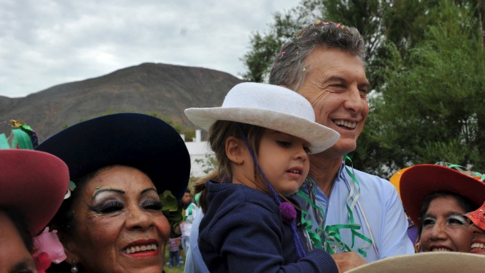 Argentina's President Macri holding his daughter Antonia poses alongside locals as he takes part in a carnival celebration in the Argentine northern town of Purmamarca
