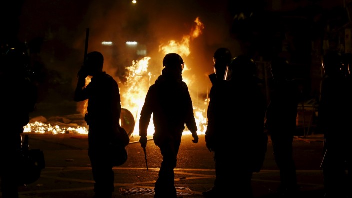 A riot policeman walks in front of a fire set by protesters at a junction in Mongkok district in Hong Kong