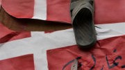 Mohammed-Zeichnungen: Ein Demonstrant in Palästina hält ein Messer an eine dänische Flagge, auf der ein Schuh befestigt ist, ein Zeichen der Missachtung.