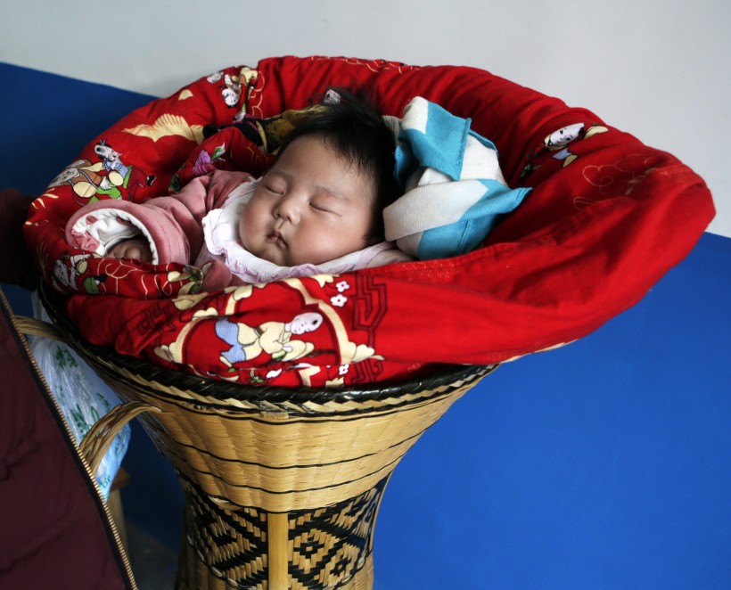 A 3-month-old ethnic Tujia baby girl is pictured next to her father during celebrations marking the Lunar New Year in Ziqiu town, Changyang county of ChinaâÄÖs Hubei province
