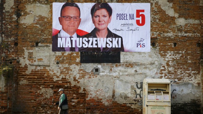 A man passes by an election poster depicting Law and Justice's candidate Matuszewski accompanied by the party's candidate for Prime Minister Szydlo in Leczyca