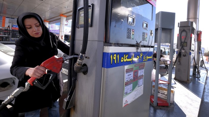 An Iranian woman puts a nozzle back after refuelling her car at a petrol station in Tehran