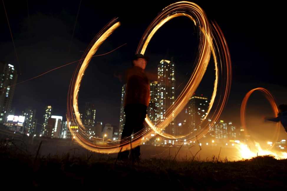 A participant whirls cans filled with burning wood chips during a celebration ahead of 'Jeongwol Daeboreum' (Great Full Moon), at a park in Seoul