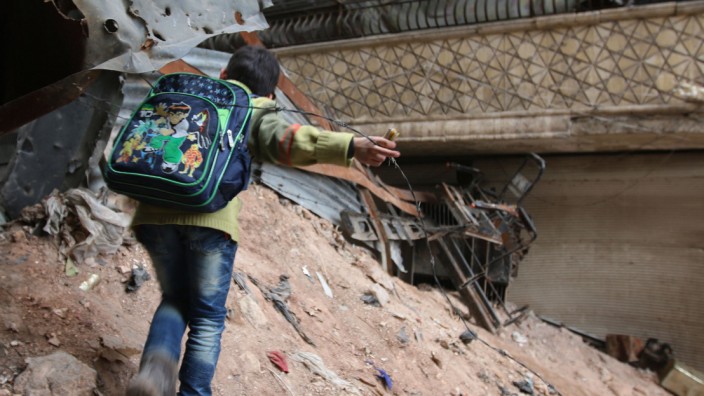 Krieg in Syrien: Schweigen nun bald die Waffen? Ein Kind klettert über den Schutt zerbombter Häuser in Aleppo.