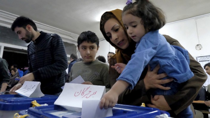 Iranian woman holding her daughter casts her ballot during elections for the parliament and Assembly of Experts, in Tehran