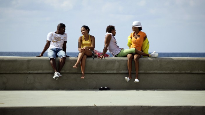 Youths sit on Havana's El Malecon seafront bolulevard