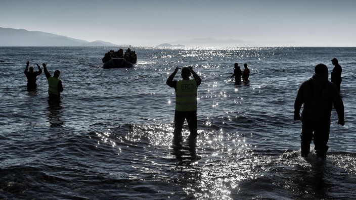Flüchtlinge: Ein Boot erreicht Lesbos, Helfer gestikulieren: Auf dem EU-Gipfel wurde eine Einigung vorbereitet, die Überfahrten über die Ägäis verringern soll.
