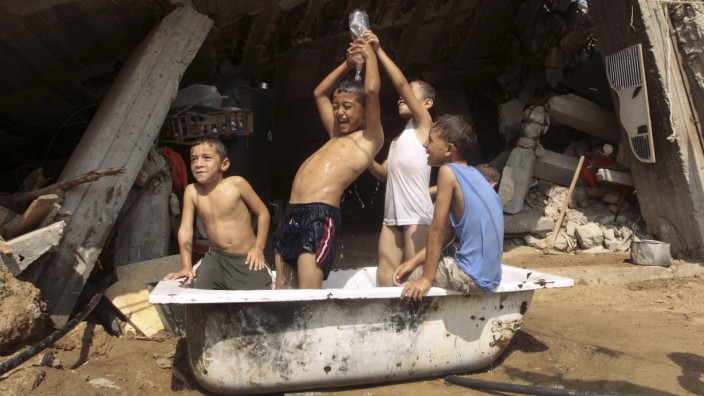 Palestinian boys bathe in front of a house, destroyed during the three-week offensive Israel launched last December, in the northern Gaza Strip