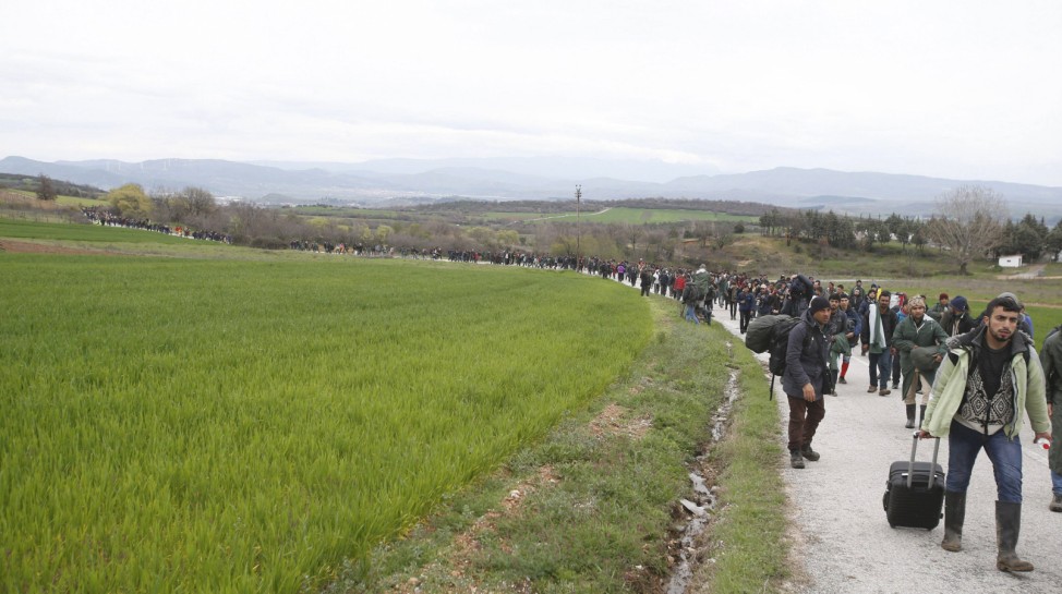 Migrants walk along a path looking for a way to cross the Greek-Macedonian border near the village of Idomeni