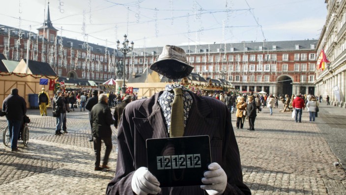 Street performer poses with iPad showing time of 12:12:12 in Madrid