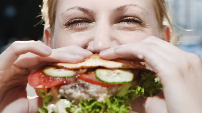 Young woman eating a hamburger model released PUBLICATIONxINxGERxSUIxAUTxHUNxONLY FEXF000039