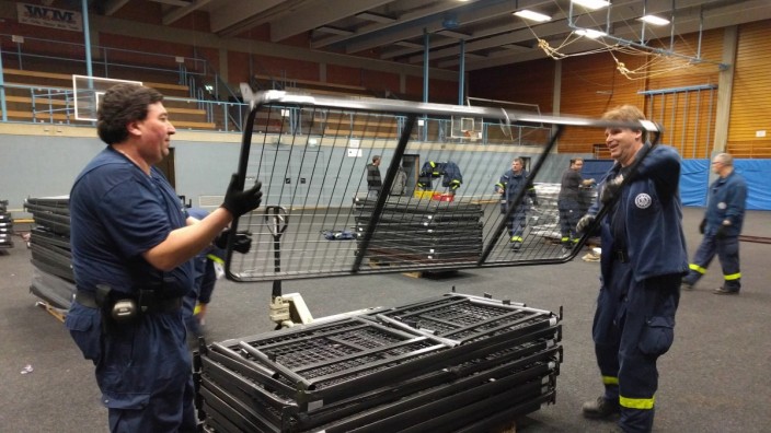 Turnhalle in Vaterstetten: Ab ins Lager: Einsatzkräfte des Technischen Hilfswerks beim Abbau der Stockbetten in der Turnhalle.
