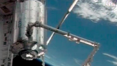 Raumstation ISS: Das Columbus Modul wird mit einem Roboterarm von der Atlantis gehoben, um an der ISS angekoppelt zu werden.