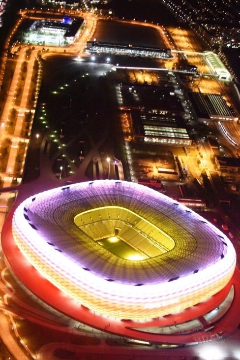 Nachtluftbild der rot - weiß angestrahlten Allianz Arena in München im Bundesland Bayern