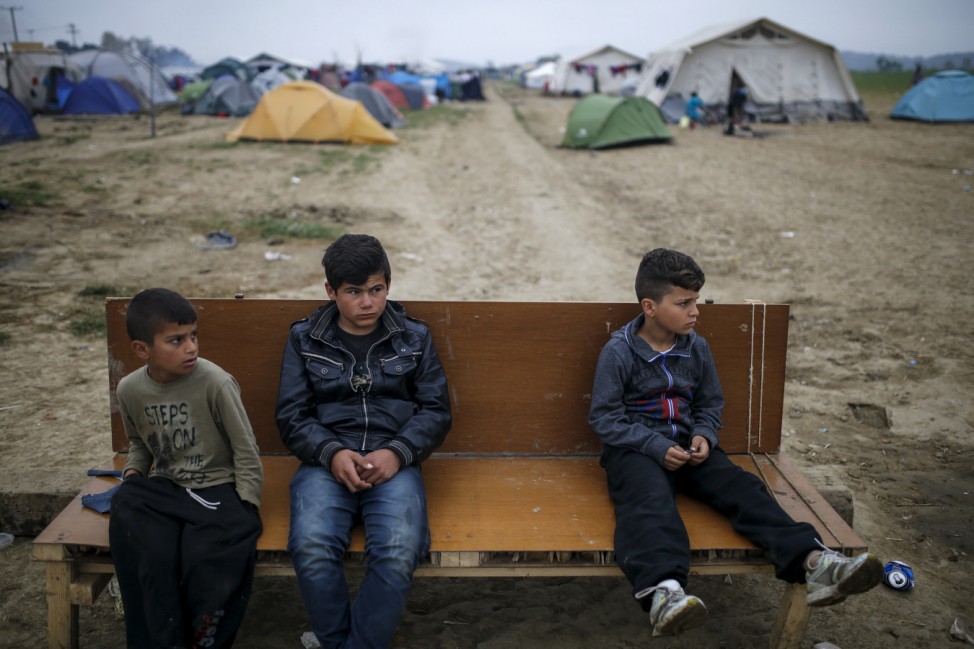 Children sit on a bench at a makeshift camp for migrants and refugees at the Greek-Macedonian border near the village of Idomeni