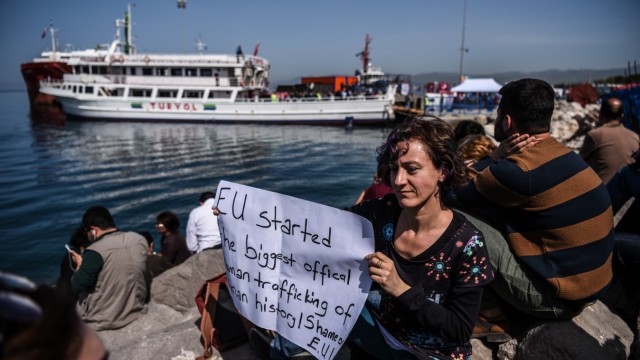 Türkei: Zurück in der Türkei: Flüchtlinge erreichen auf einer Fähre die Insel Izmir, eine Aktivistin protestiert gegen die aus ihrer Sicht ungerechte Aktion.