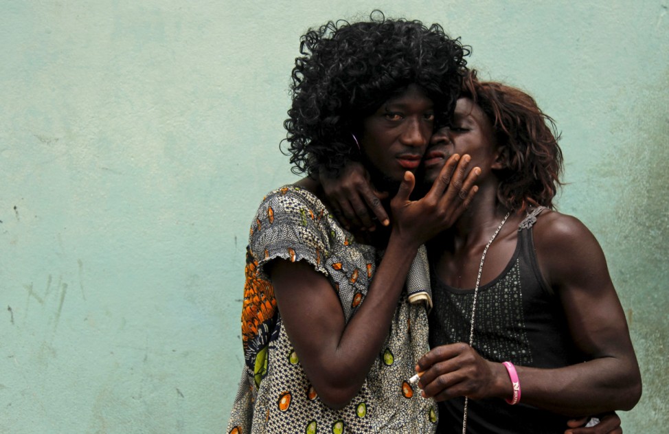 Men dressed as women kiss as they take part in a parade during the Popo (Mask) Carnival of Bonoua, east of Abidjan