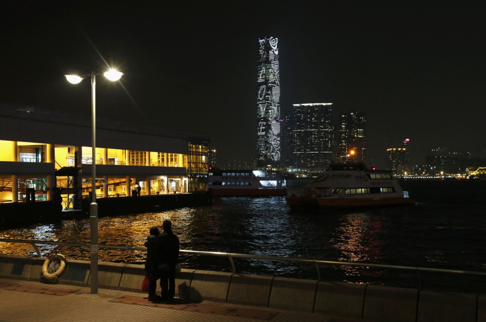 A couple stands on the waterfront as a love sign is lit on ICC in Hong Kong
