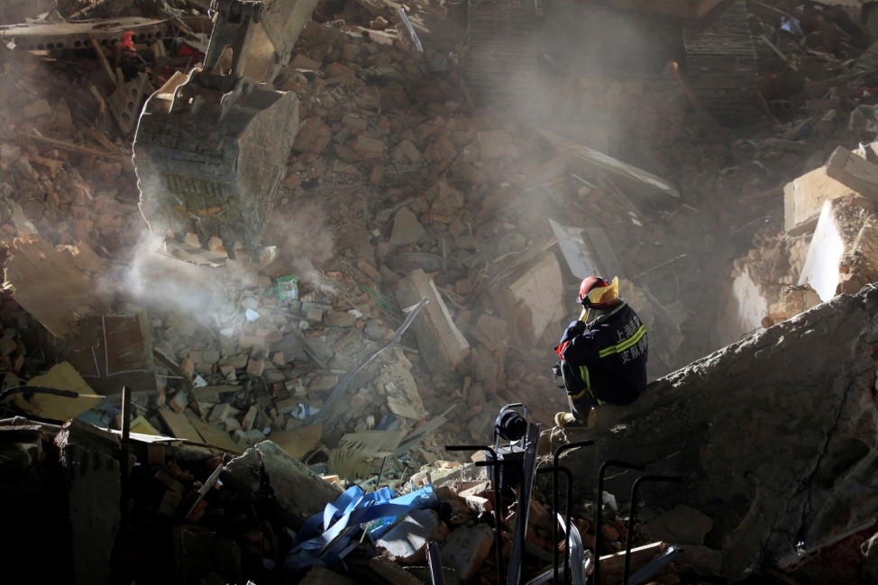 A rescue worker searches at the site after a three-storey residential building collapsed in Shanghai