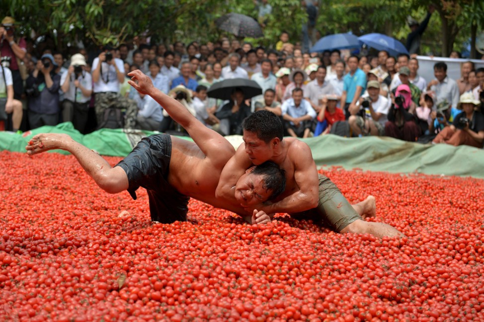 Contestants wrestle in a pool of tomatoes during a local culture and tourism festival in Tianyang