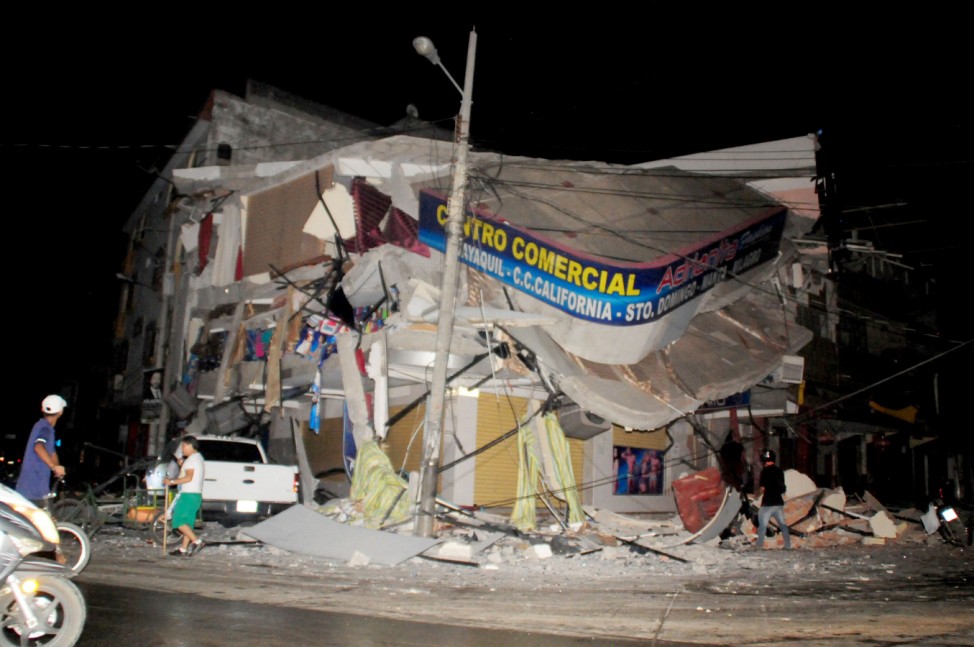 People walk near a damaged house after an earthquake struck off the Pacific coast in Manta