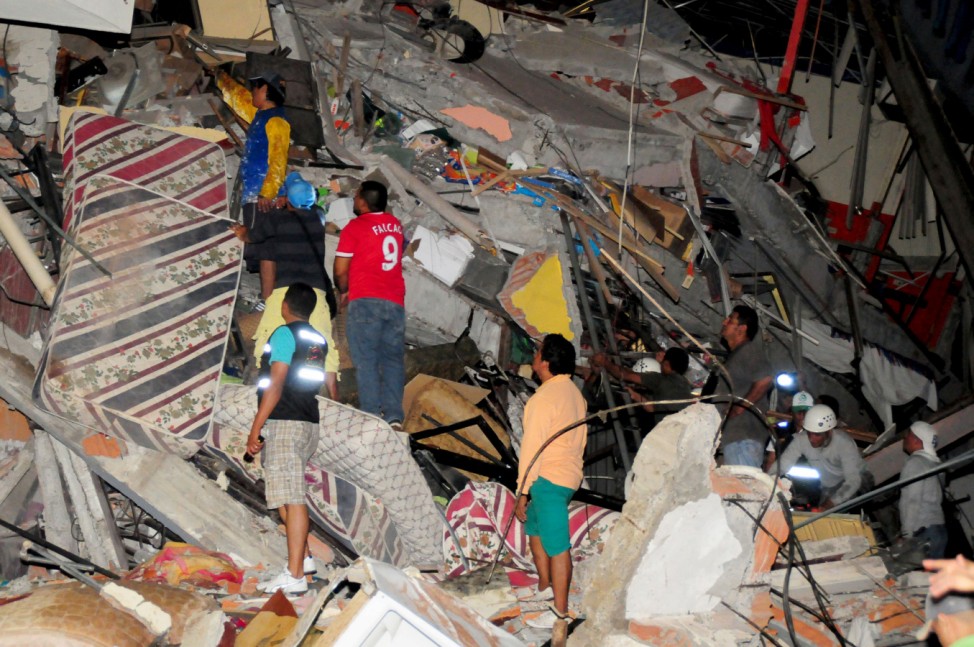 People stand on the debris of a building after an earthquake struck off the Pacific coast in Manta