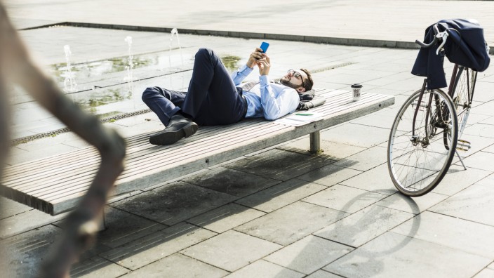 Young businessman lying on bench, working model released Symbolfoto PUBLICATIONxINxGERxSUIxAUTxHUNxO