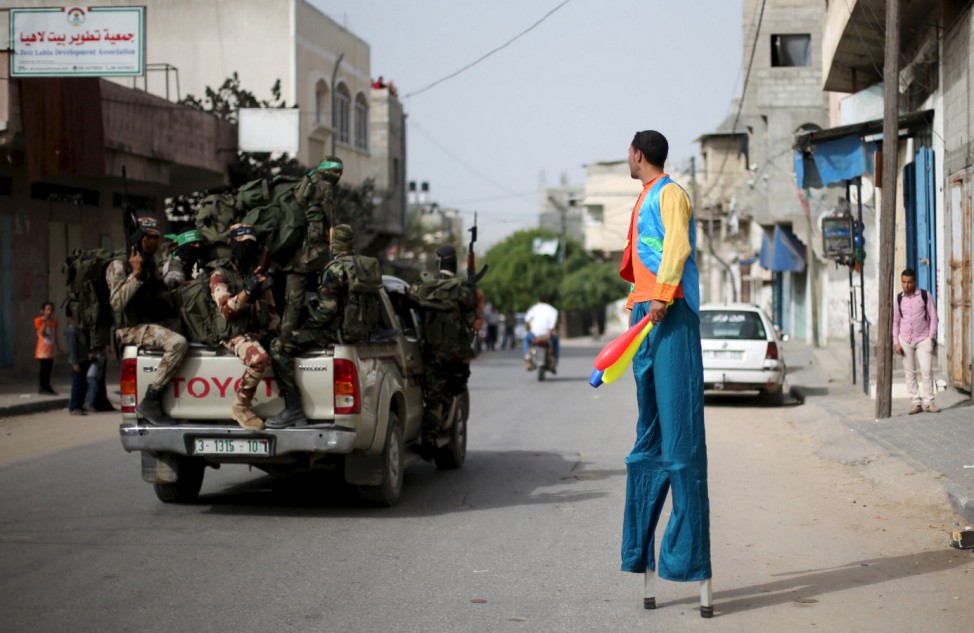 Palestinian Majed Kalluob, 24, walks with stilts as he looks at Hamas militants riding a pickup truck on a street in the northern Gaza Strip