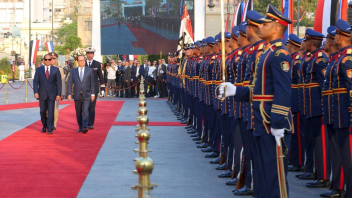 Egyptian President Abdel Fattah al-Sisi and his French counterpart Francois Hollande review honour guard during a welcome ceremony at al-Quba Presidential Palace, in Cairo