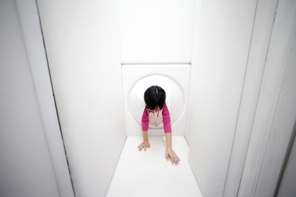 An employee experiences 'birth' through a latex 'womb' at a Wake and Death Experience Pavilion in Shanghai