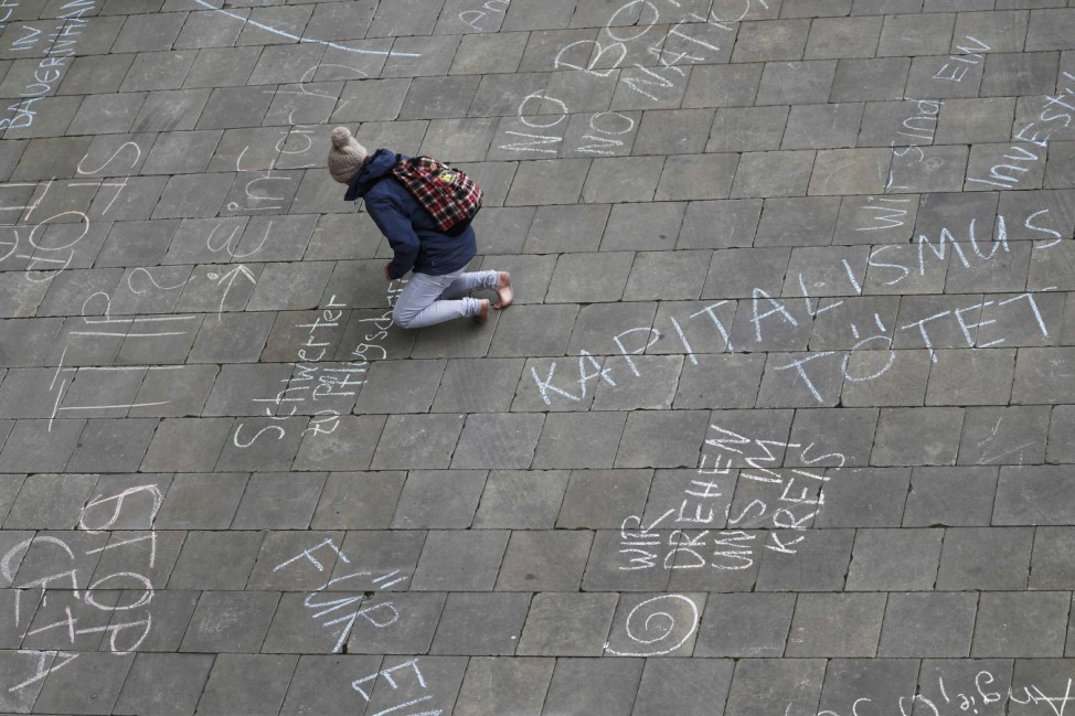 A protester writes text during a demonstration against TTIP free trade agreement ahead of U.S. President Obama's visit in Hannover