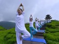 People perform yoga at a tea culture park in Enshi
