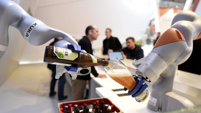 Robots in the Kuka stand pour a beer into a glass at the Hannover Messe industrial trade fair in Hanover