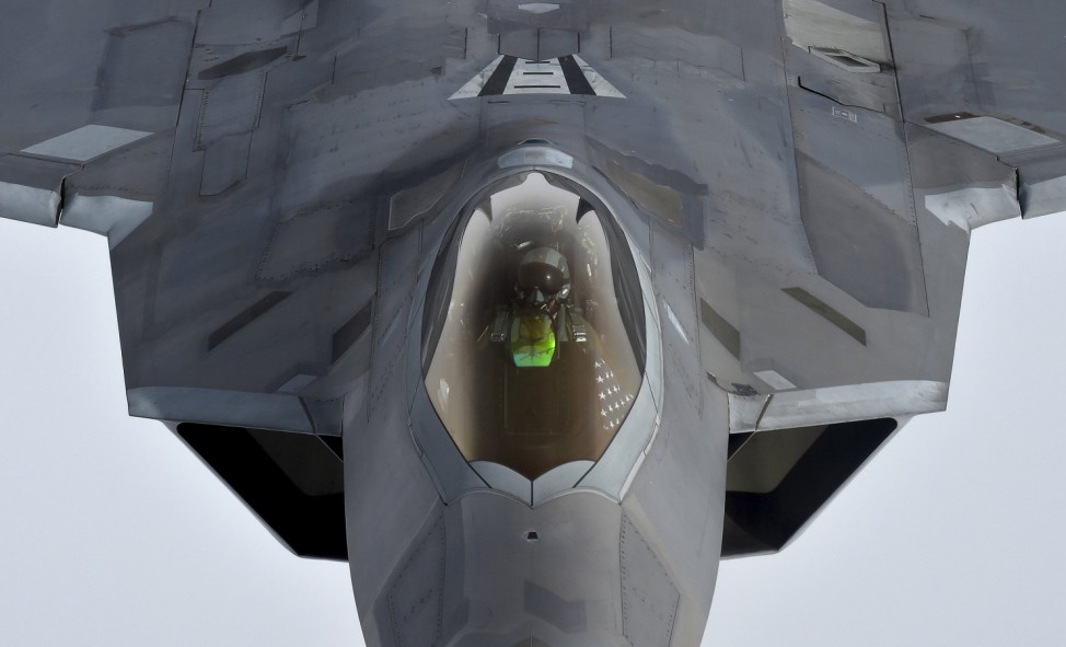 A pilot looks up from a U.S. F-22 Raptor fighter as it prepares to refuel in mid-air with a KC-135 refuelling plane over European airspace during a flight to Britain from Mihail Kogalniceanu air base in Romania