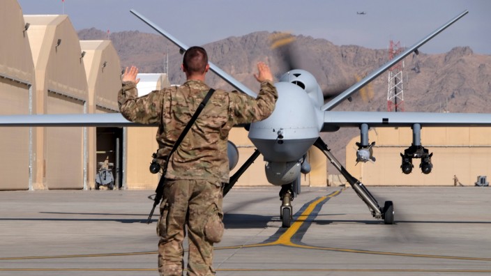 A U.S. airman guides a U.S. Air Force MQ-9 Reaper drone as it taxis to the runway at Kandahar Airfield, Afghanistan