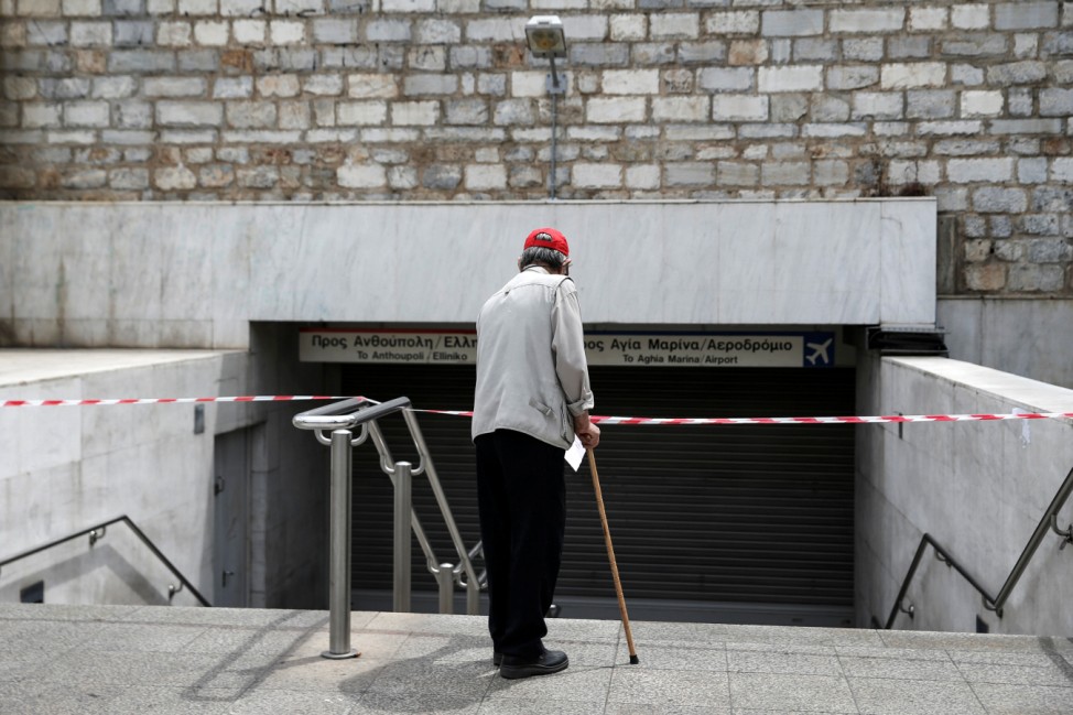 A commuter reads a notice at the closed entrance of the central Syntagma square Metro station during a 48-hour general strike against tax and pension reforms in Athens