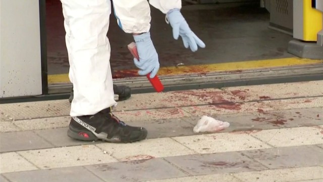 An police investigator looks at bloodstained footprints leading out of a train and on a platform  following a knife attack in Grafing train station, south east of Munich, Germany