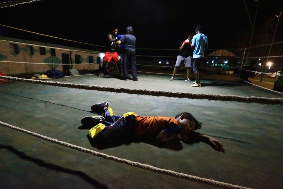 A boy sleeps inside the ring as Arafat Abkar, 22, practises boxing at Nile Club in Khartoum