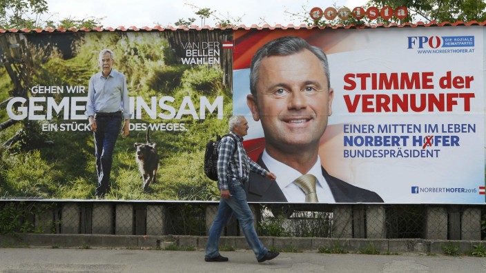 A man passes presidential election campaign posters of Van der Bellen and Hofer in Vienna