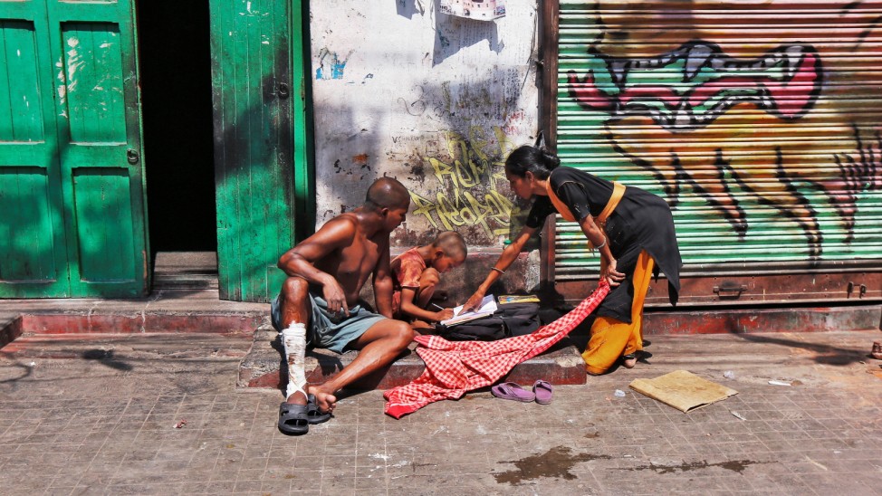 Homeless couple Kiran and Vishal help their son Kanish with his studies outside a closed shop on a pavement in Kolkata