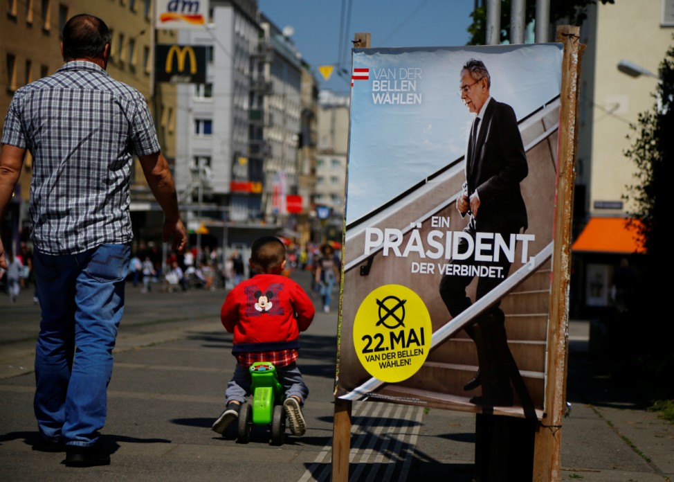 A man passes by an election campaign poster of presidential candidate Van der Bellen in Vienna