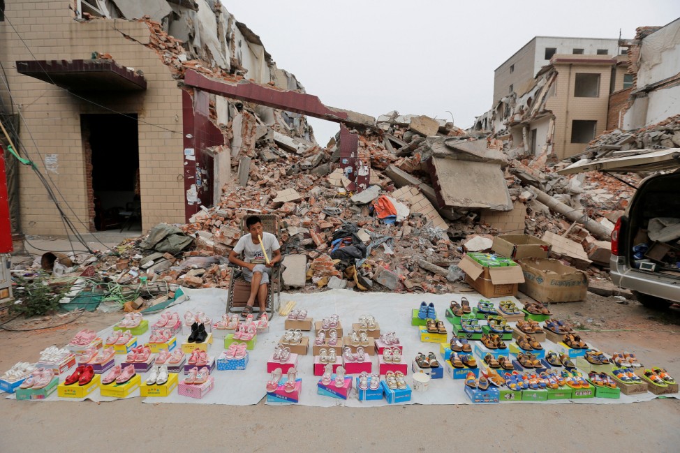 A vendor waits for customers at a market in an urban village under demolition in Zhengzhou
