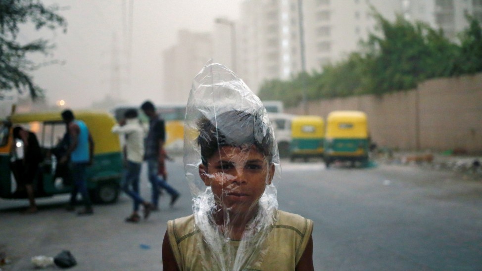 A young boy uses a plastic bag to protect himself from a dust storm in New Delhi