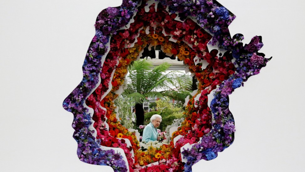 Britain's Queen Elizabeth II is pictured through a gap in a floral exhibit by the New Covent Garden Flower Market, which features an image of the Queen, during a visit to the 2016 Chelsea Flower Show in central London