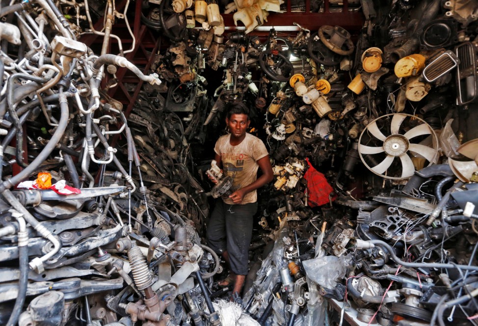 A worker carries a part of a used car inside a shop at a second-hand automobile parts market in Mumbai