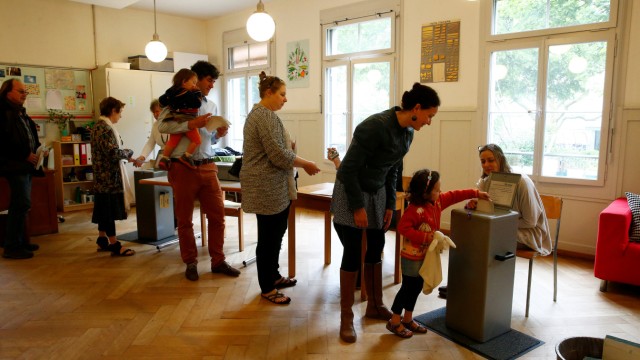 People cast their ballots during a vote on whether to give every adult citizen a basic guaranteed monthly income of 2,500 Swiss francs ($2,560), in a school in Bern