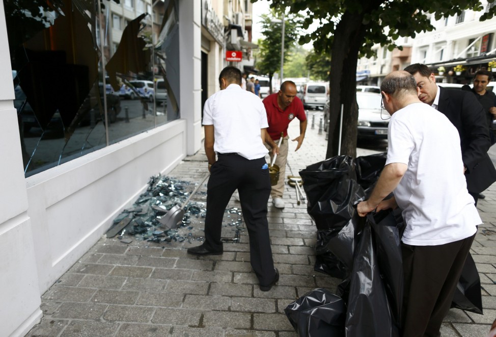 People remove glass near the site where a Turkish police bus was targeted in a bomb attack in a central Istanbul district