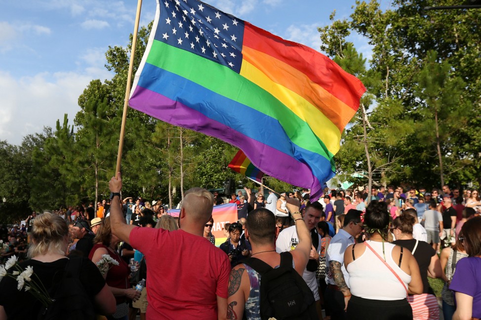 A man holds a rainbow U.S. flag during a vigil for the Pulse night club victims following last weeks shooting in Orlando