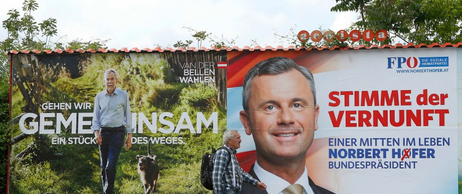 A man passes presidential election campaign posters of Van der Bellen and Hofer in Vienna